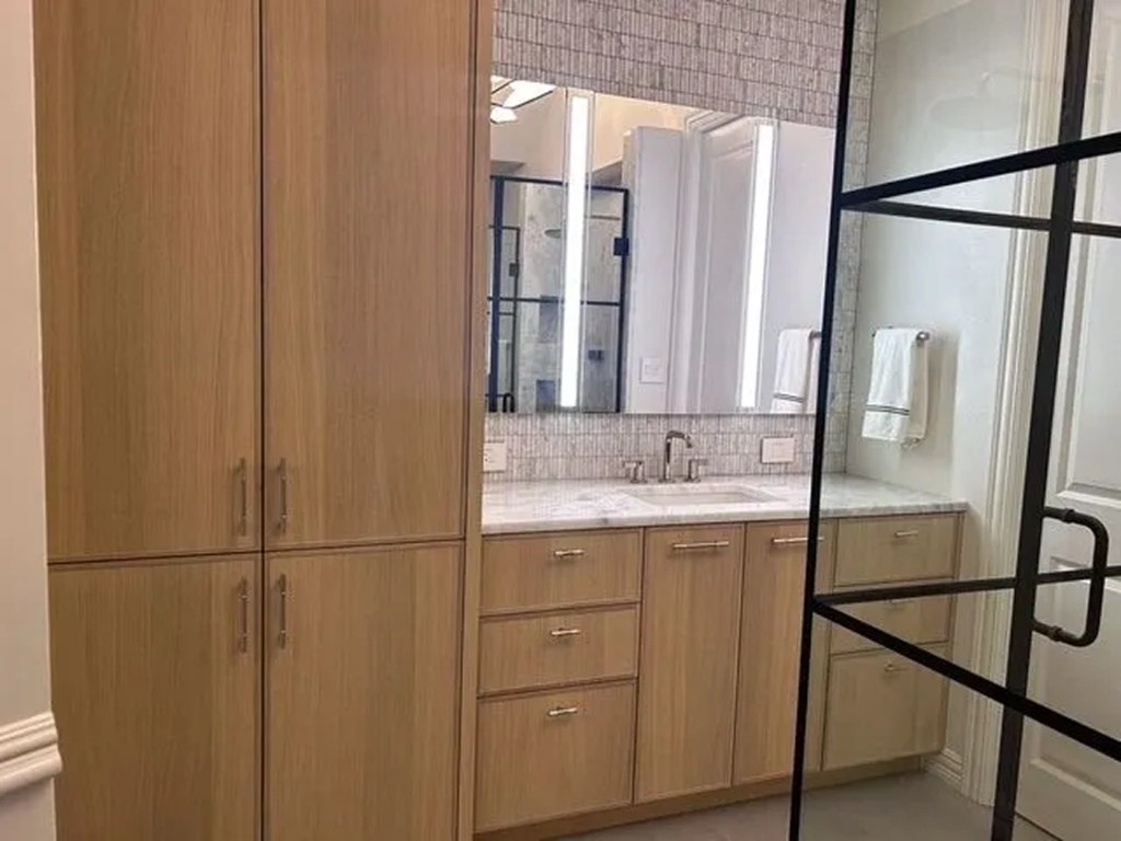 Vanity with marble countertop, mirror lighting, and grey mosaic backsplash