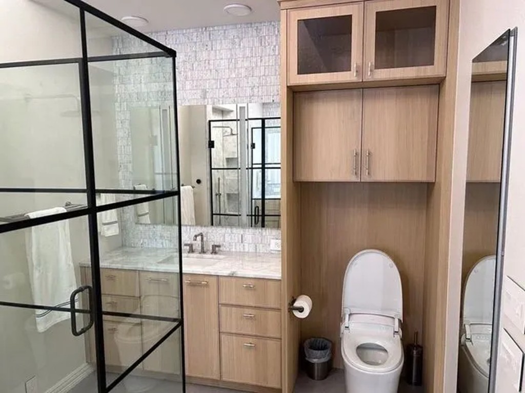Light wood vanity with illuminated mirror cabinet and mosaic tile wall