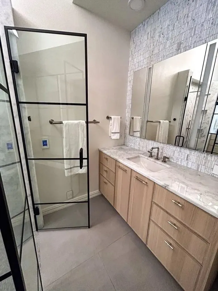 Walk-in shower with black grid glass enclosure and marble slab walls