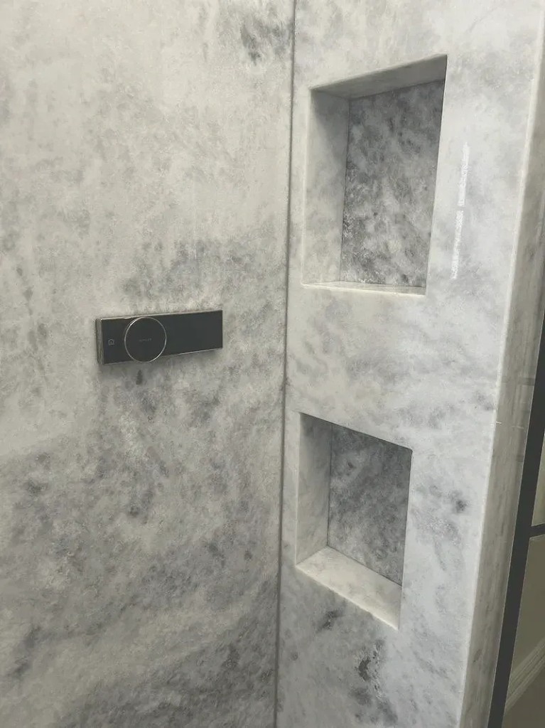 Glass shower enclosure with vanity and tall cabinetry in background