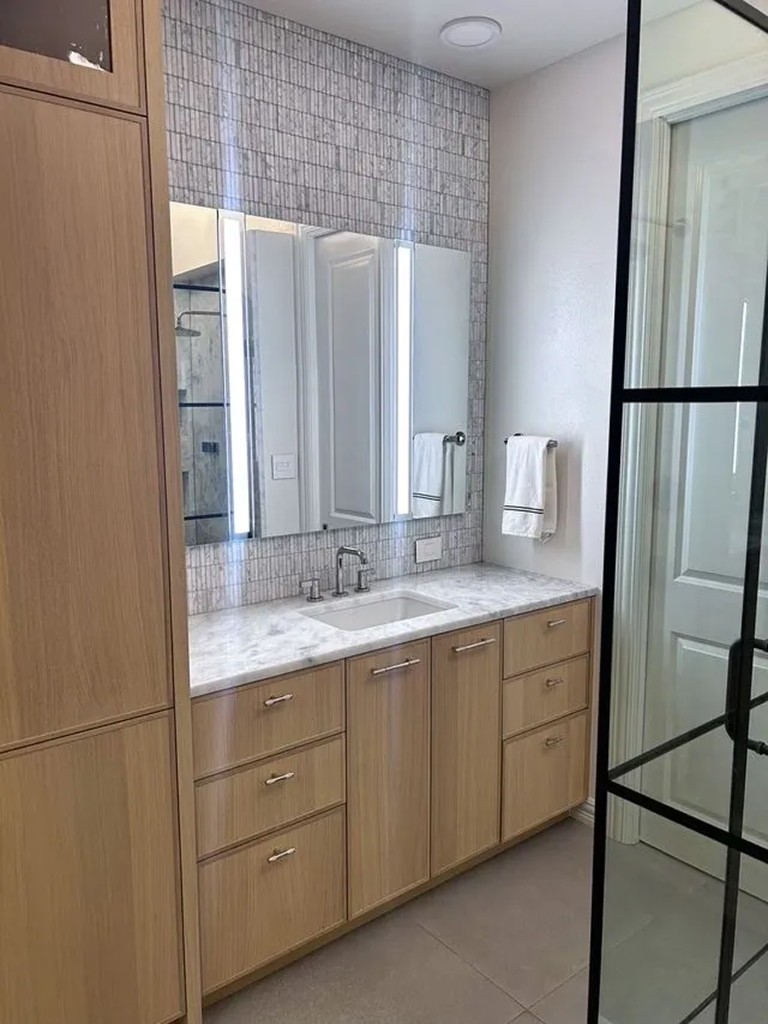 Long wood vanity with mosaic backsplash and black-framed shower door