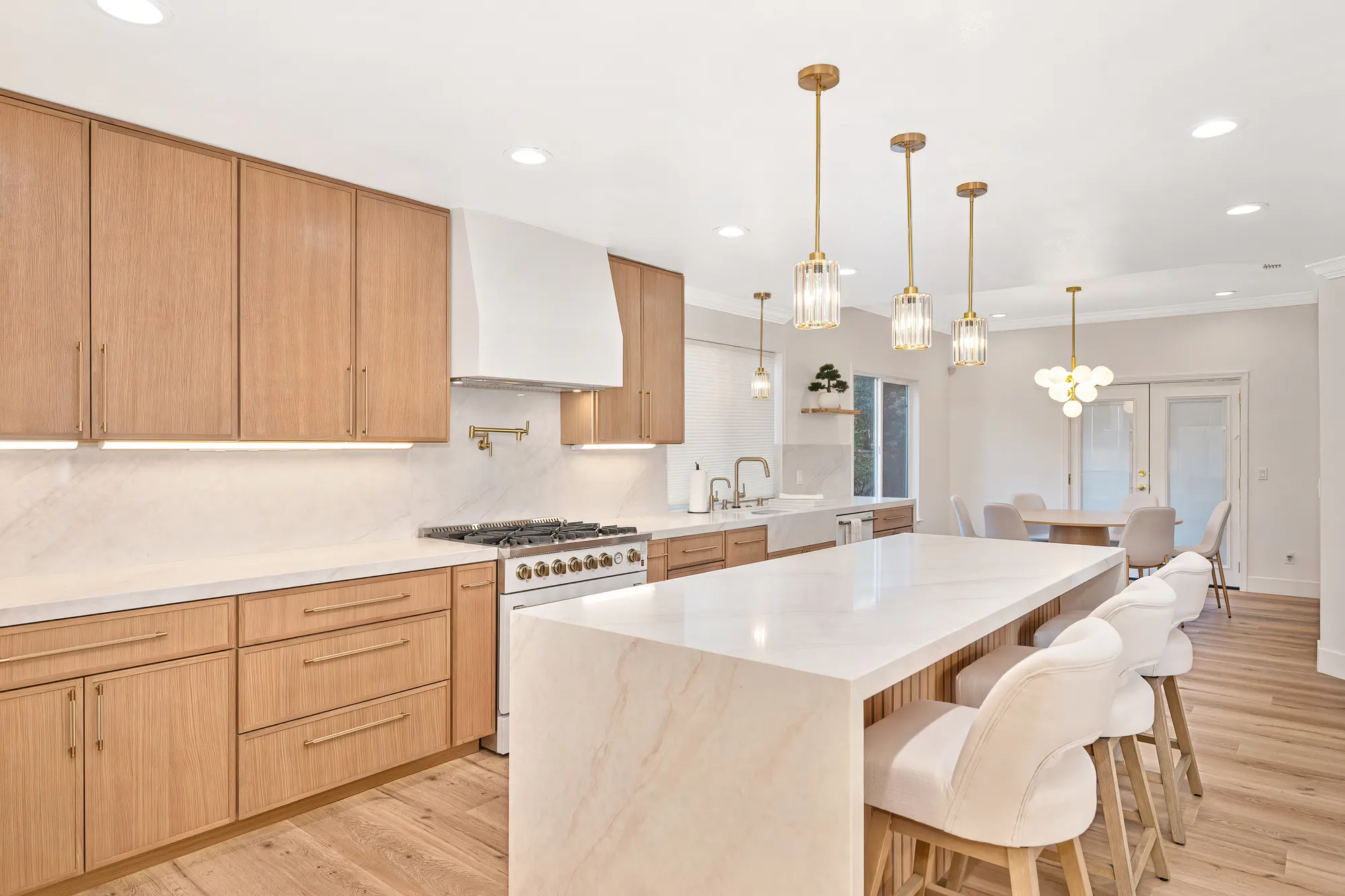 Luxury kitchen remodel with oak cabinetry, marble island, and gold accents
