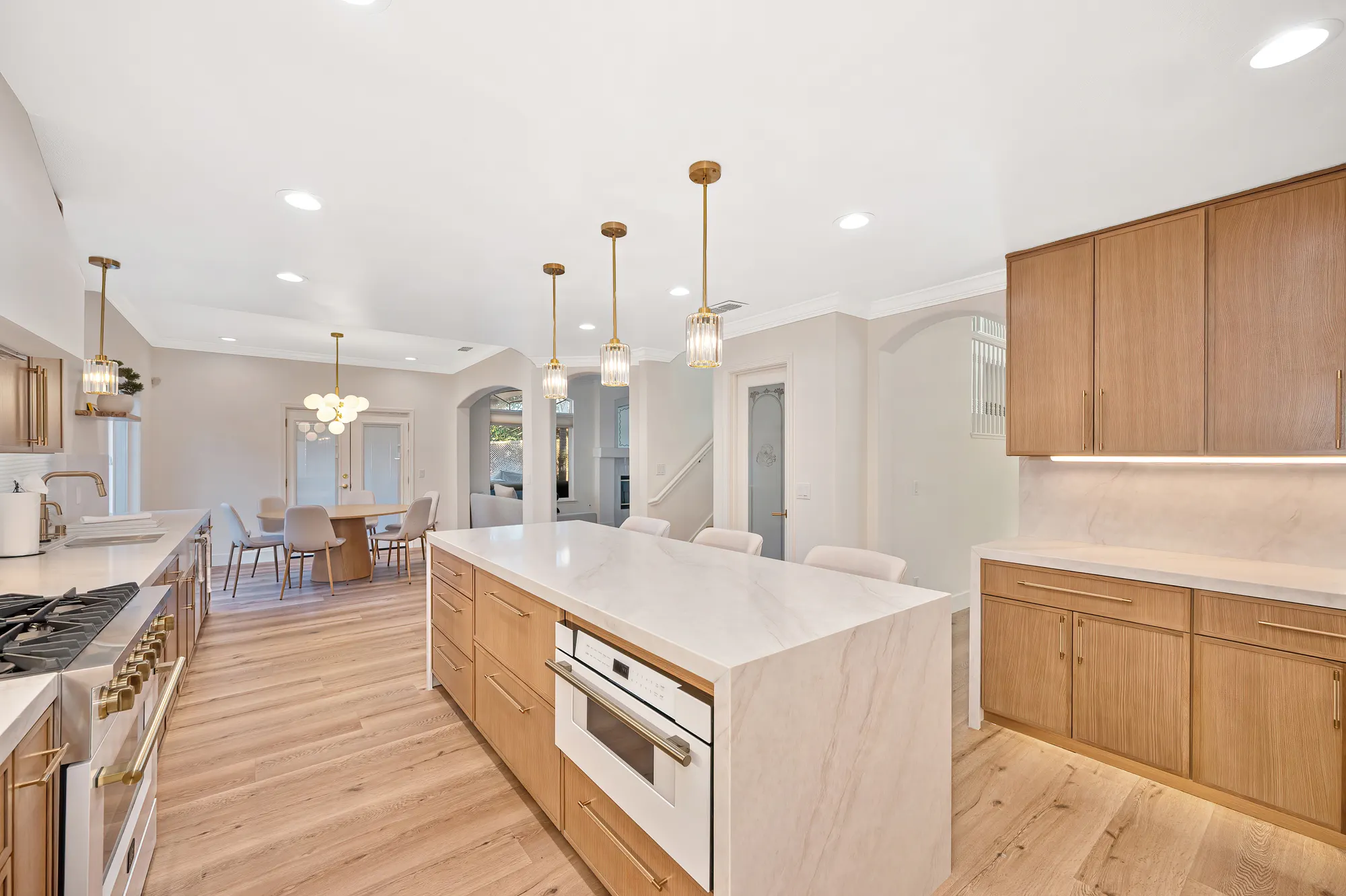 Luxury kitchen remodel with oak cabinetry, marble island, and gold accents