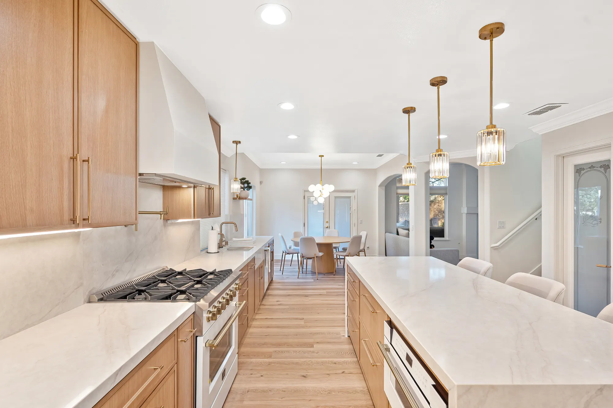 Luxury kitchen remodel with oak cabinetry, marble island, and gold accents