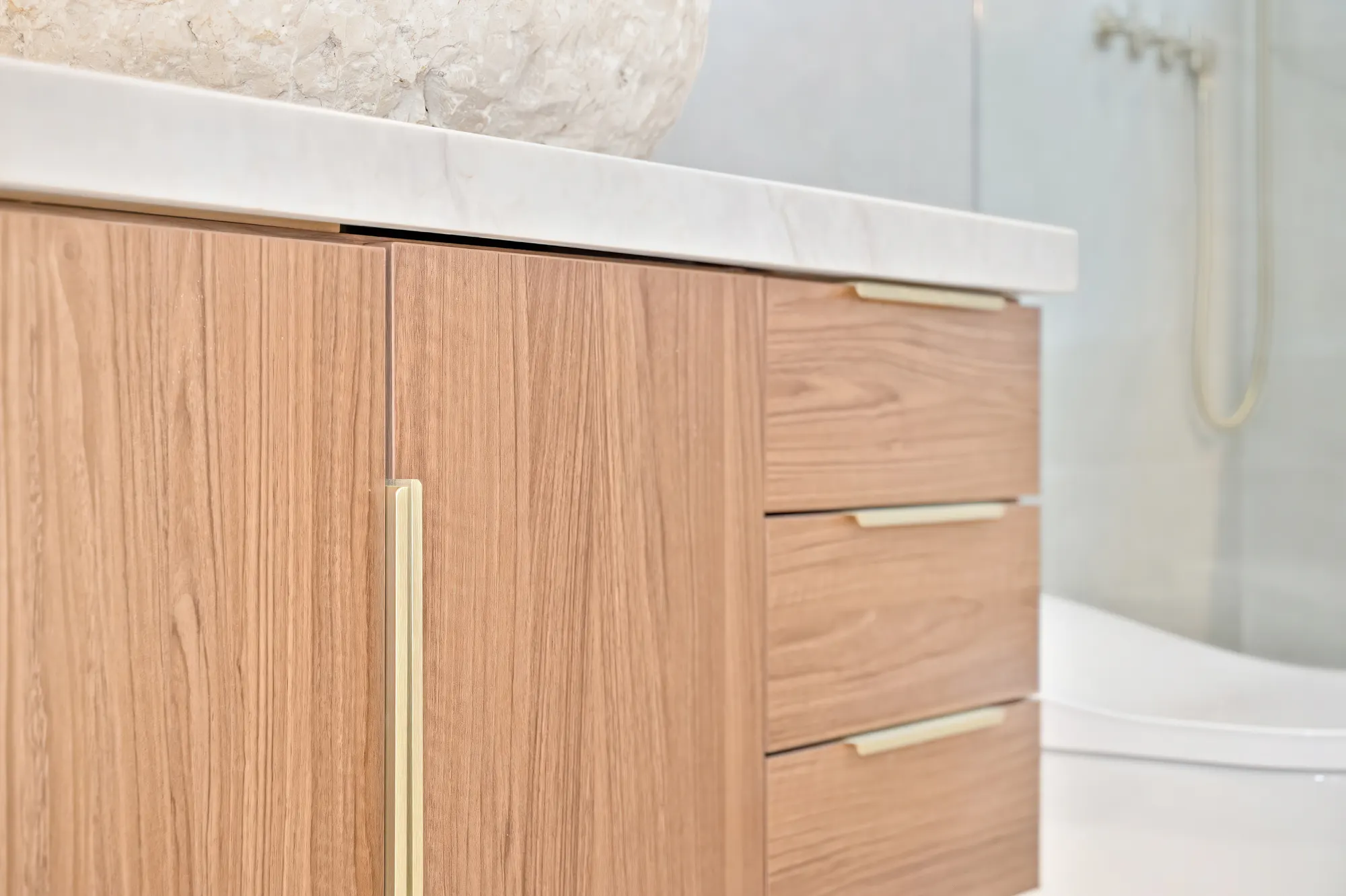Bathroom vanity with natural stone vessel sink and gold fixtures