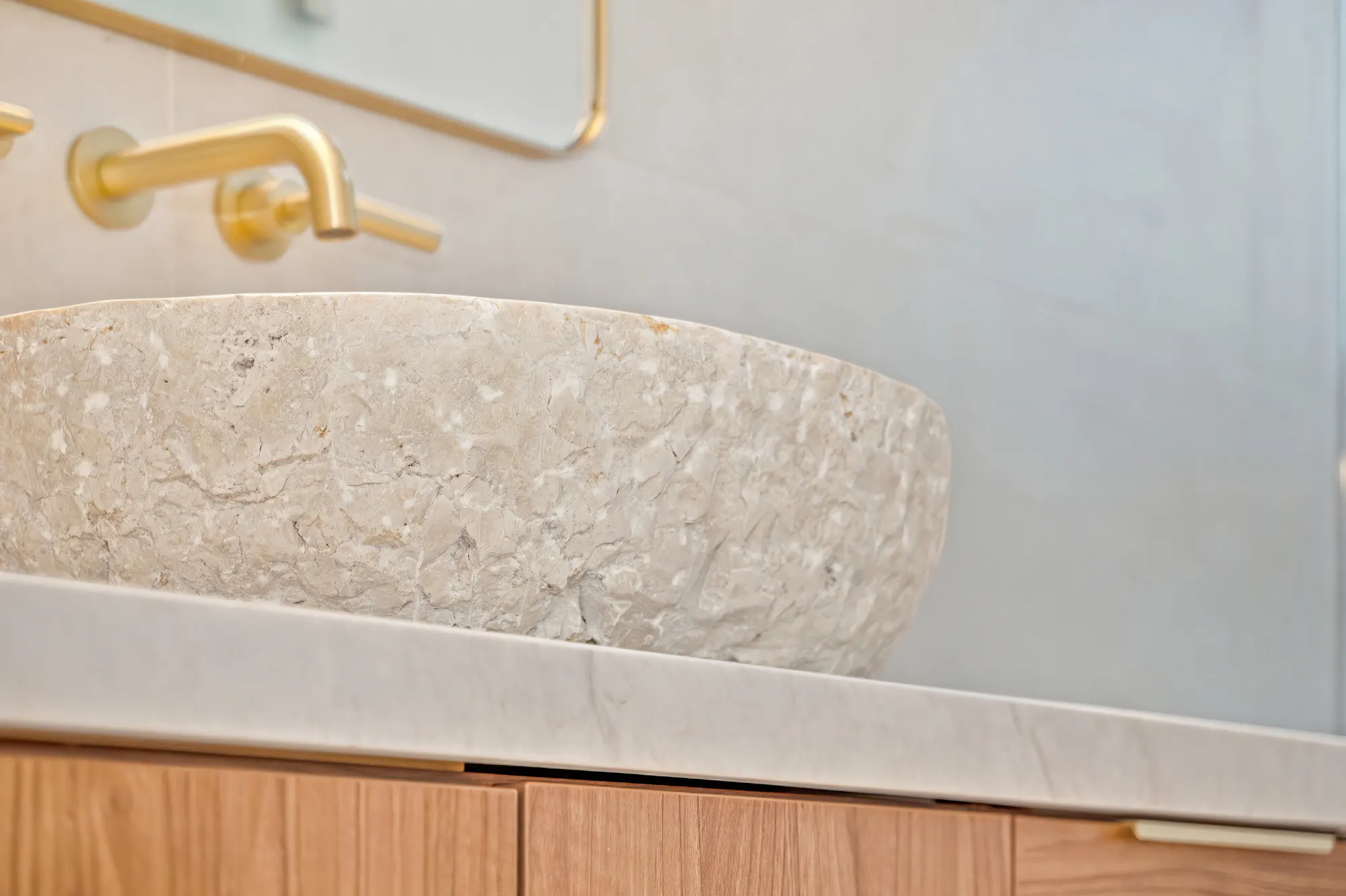 Bathroom vanity with natural stone vessel sink and gold fixtures