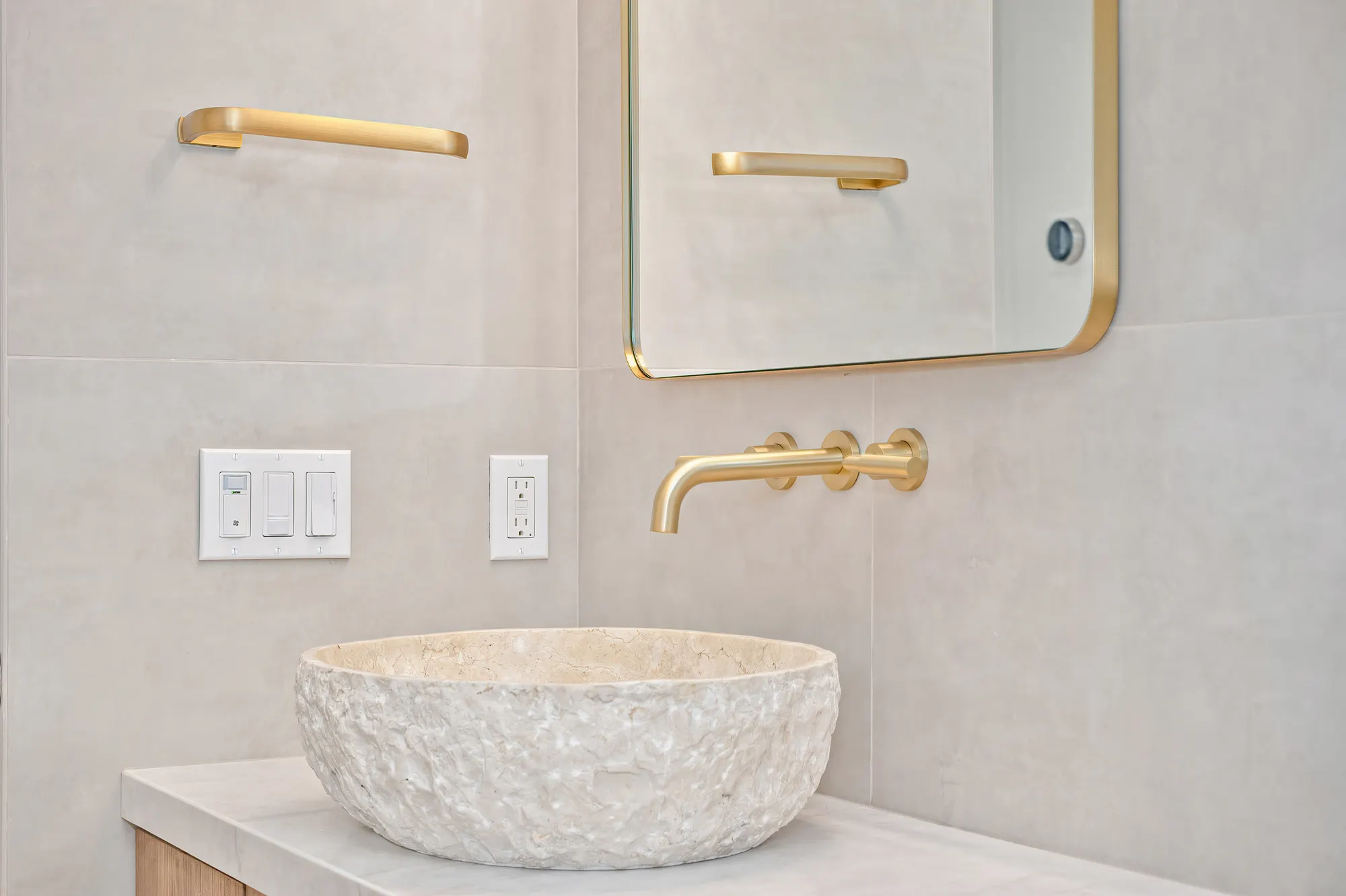 Bathroom vanity with natural stone vessel sink and gold fixtures
