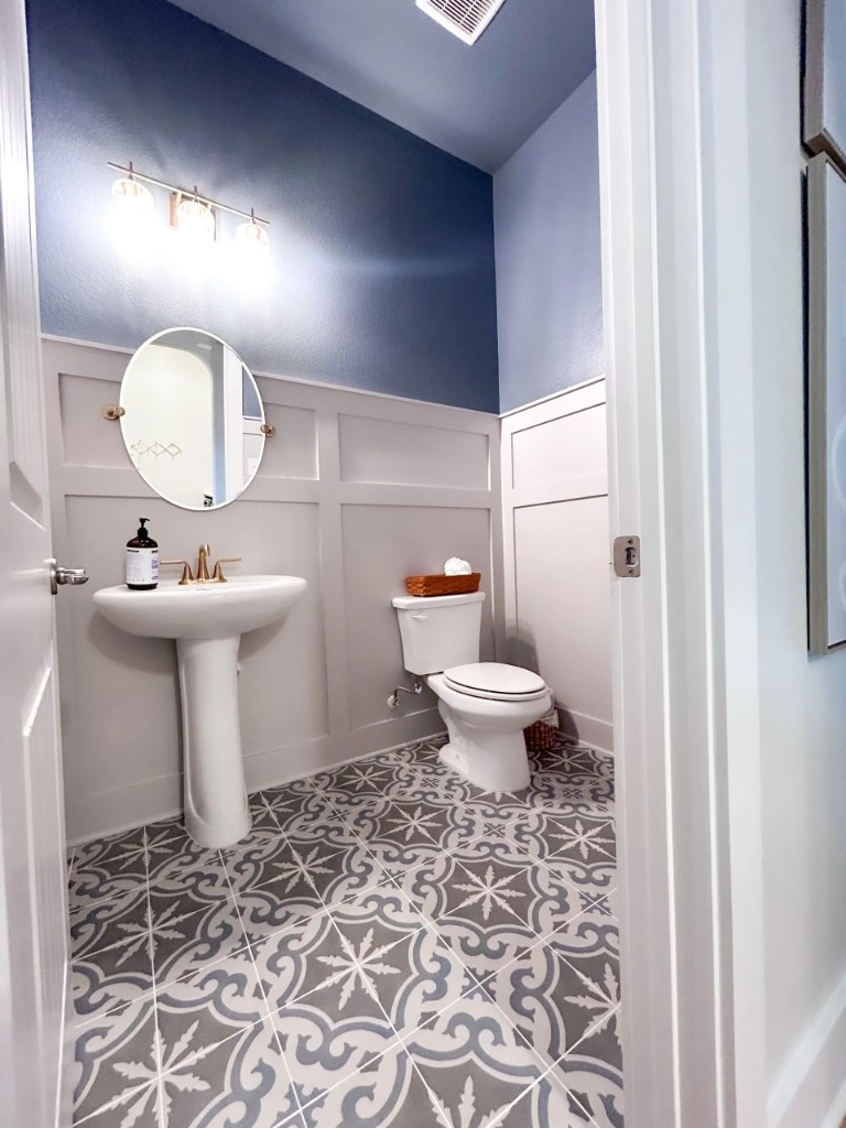 Powder room with pedestal sink, blue walls, and patterned floor tile